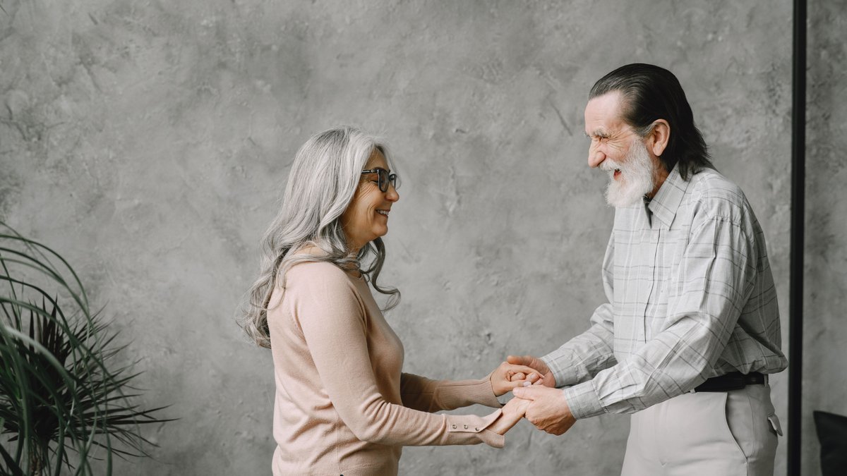 Joyful elderly couple dancing indoors, expressing love and happiness.