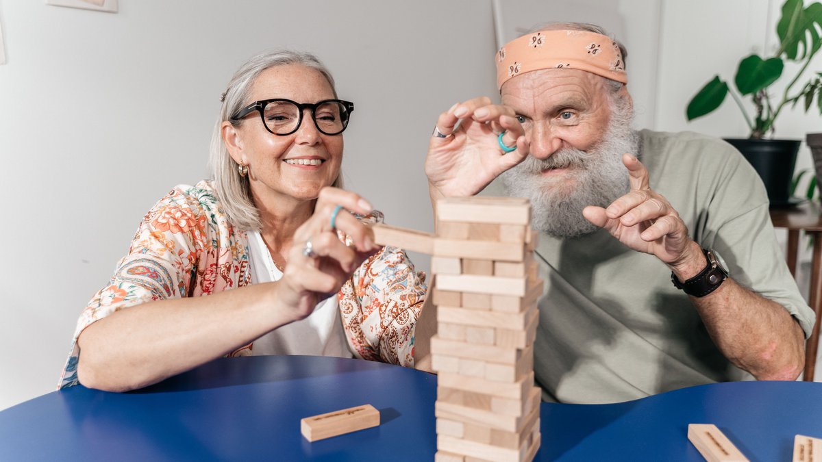 Senior couple enjoying a game of Jenga indoors, sharing laughter and fun.