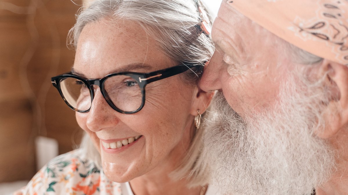 Elderly couple with eyeglasses sharing a joyful moment indoors, exuding love and happiness.