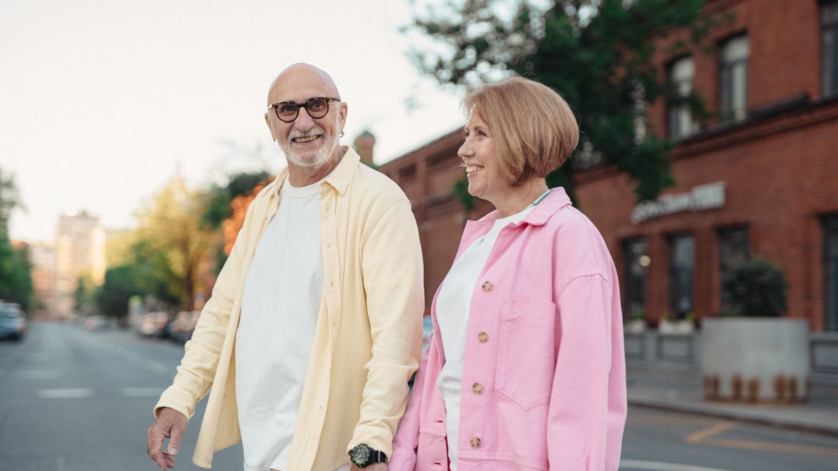 Happy senior couple enjoying a walk together outdoors, holding hands and smiling.
