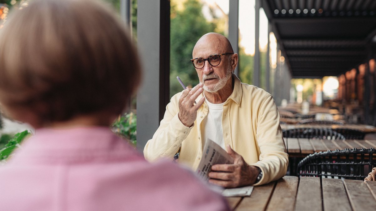Elderly couple conversing at an outdoor cafe, enjoying a peaceful moment together.
